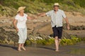 Lovely senior mature couple on their 60s or 70s retired walking happy and relaxed on beach sea shore in romantic aging together Royalty Free Stock Photo