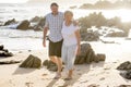 Lovely senior mature couple on their 60s or 70s retired walking happy and relaxed on beach sea shore in romantic aging together