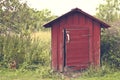 Lovely small red shed in summertime. Beautiful summer season specific photograph. Small house/cabin/shed together with rich green Royalty Free Stock Photo