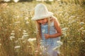 Lovely smiling blond girl in a field at sunset. Cute girl in a flowering field sniffs flowers. Ukrainian in a hat and dress near Royalty Free Stock Photo