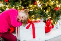 pretty little girl in a dress waiting at the foot of the Christmas tree for the opening of presents Royalty Free Stock Photo