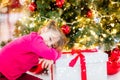 pretty little girl in a dress waiting at the foot of the Christmas tree for the opening of presents Royalty Free Stock Photo