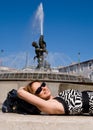 Lovely smiling woman lying by fountain in Rome