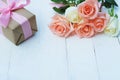 Lovely soft orange pink color rose tied by pink ribbon and brown gift box on white wood table background, sweet valentine present