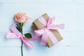 Lovely soft orange pink color rose tied by pink ribbon and brown gift box on white wood table background, sweet valentine present