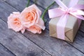 Lovely soft orange pink color rose tied by pink ribbon and brown gift box on wood table background, sweet valentine present