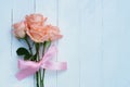 Lovely soft orange pink color rose tied by pink ribbon and brown gift box on white wood table background, sweet valentine present