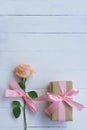 Lovely soft orange pink color rose tied by pink ribbon and brown gift box on white wood table background, sweet valentine present