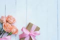 Lovely soft orange pink and white color rose tied by pink ribbon and brown gift box on white wood table background, sweet