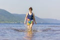 Lovely sporty mature woman stands and splashes water on the beach on the Volga river on a summer sunny day against the background Royalty Free Stock Photo