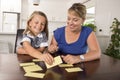 Lovely sweet and happy 6 years old daughter learning reading with flash card words game at home kitchen playing with her young bea Royalty Free Stock Photo