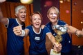 Lovely team of senior and young women celebration win with golden cup together in locker room