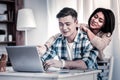 Pleasant couple cuddling together and looking on the screen