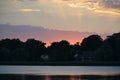 Tranquil pink and golden sunset above a lake or river; cottage in the shadows Royalty Free Stock Photo