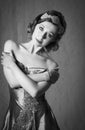 Lovely twenties woman wearing diamond hair accessory and bracelet, posing in a vintage grey evening dress