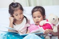 Lovely twin sister two child girls having fun to read a cartoon