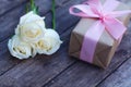 Lovely soft white color rose tied by pink ribbon and brown gift box on wood table background, sweet valentine present concept