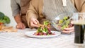 A lovely wife is serving a salad on a plate after cooking it with her husband in the kitchen Royalty Free Stock Photo