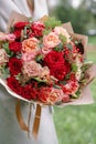 Lovely woman holding a beautiful autumn bouquet. flower arrangement with carnations and red garden roses. Color pink Royalty Free Stock Photo