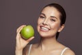 Lovely woman holding green apple and smiling on brown background Royalty Free Stock Photo