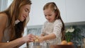 Lovely woman daughter cooking at kitchen. Mom removing pastry from child hands Royalty Free Stock Photo