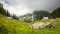 Lovely wooden cottages stand near a pine forest covered mountain in the tranquil Julian Alps. Royalty Free Stock Photo