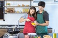 Lovely young Asian couple with casual clothes is helping to prepare for cooking food for breakfast, lunch or dinner as omelet Royalty Free Stock Photo