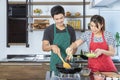 Lovely young Asian couple with casual clothes is smiling, cooking healthy food by fresh organic vegetables for breakfast, lunch Royalty Free Stock Photo