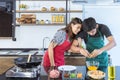 Lovely young Asian couple in love with casual clothes, handsome house husband is cooking and preparing as omelet for breakfast Royalty Free Stock Photo