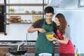 Lovely young Asian couple in love with casual clothes, handsome house husband is cooking and preparing by beating eggs to omelet Royalty Free Stock Photo