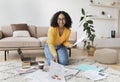 Lovely young black woman sitting on floor with laptop and documents, working or learning from home, free space Royalty Free Stock Photo