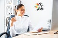 Lovely young businesswoman reading report and holding cup of coffe Royalty Free Stock Photo