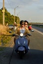 Lovely young couple of friends enjoying riding retro scooter on the road outside the city Royalty Free Stock Photo