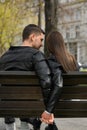 Lovely young couple holding hands together while sitting on bench outdoors, back view. Romantic date Royalty Free Stock Photo
