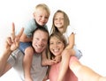 Lovely young couple taking selfie photo self portrait with mobile phone carrying son and daughter on shoulders posing happy smilin Royalty Free Stock Photo