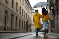 Lovely young couple with umbrella walking under rain on city street, back view Royalty Free Stock Photo