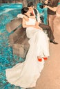 Lovely young couple in wedding suits sits on a wooden bench in the park