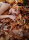 Lovely young girl is lying on autumn leaves, covered with colored autumnal leaves, with free space for your text. Royalty Free Stock Photo