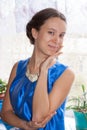 Lovely young girl is standing smiling near window and looking at camera. Royalty Free Stock Photo