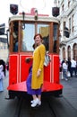 Lovely young girl stands on the step of a red historic tram in Istanbul