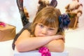 pretty little girl in a dress waiting at the foot of the Christmas tree for the opening of presents Royalty Free Stock Photo