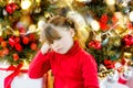 pretty little girl in a dress waiting at the foot of the Christmas tree for the opening of presents Royalty Free Stock Photo