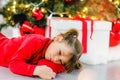 pretty little girl in a dress waiting at the foot of the Christmas tree for the opening of presents Royalty Free Stock Photo