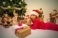 pretty little girl with a christmas hat waiting at the foot of the Christmas tree for the opening of presents Royalty Free Stock Photo