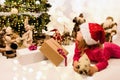 pretty little girl with a christmas hat waiting at the foot of the Christmas tree for the opening of presents Royalty Free Stock Photo