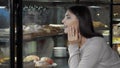 Lovely young woman choosing dessert from the display at coffee shop Royalty Free Stock Photo