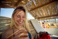 Lovely young woman drinking beer at beach, sitting on sunbed. Summertime vacation. Holiday, fun, lesiure, lifestyle concept