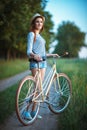 Lovely young woman in a hat with a bicycle in a park Royalty Free Stock Photo