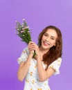 Lovely young woman holding flower bouquet and smiling while standing isolated over blue background Royalty Free Stock Photo