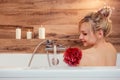 Lovely young woman holding a red sponge relaxing in bathroom Royalty Free Stock Photo